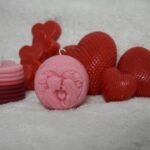 Several heart-shaped candles in red and pink.