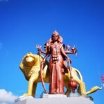 red Goddess Kali statue in front of gold lion statue during day