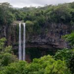 Tall waterfall cascading down a lush green cliff face.