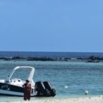A man standing on a beach next to a boat