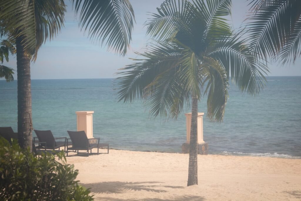 a couple of lawn chairs sitting on top of a sandy beach