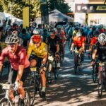 Cyclists race past cheering spectators at an event.
