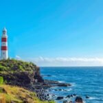 white and red lighthouse on grass field