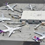 Several airplanes parked at airport gates with jet bridges attached.