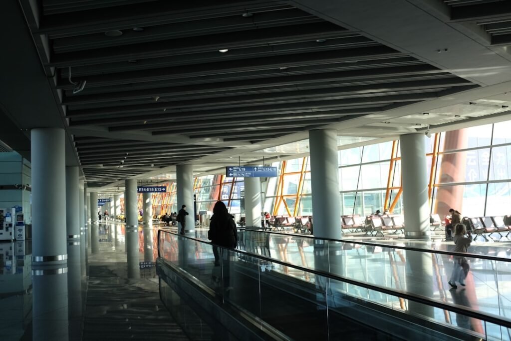 Traveler on a moving walkway in a modern airport terminal.