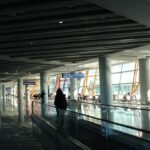 Traveler on a moving walkway in a modern airport terminal.