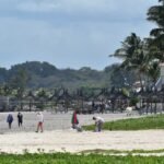 A group of people standing on top of a sandy beach