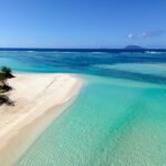 an aerial view of a beach with clear blue water