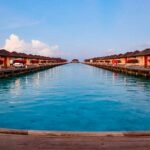 Overwater bungalows line a tranquil blue waterway.