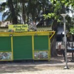 A yellow and green kiosk sitting on the side of a road