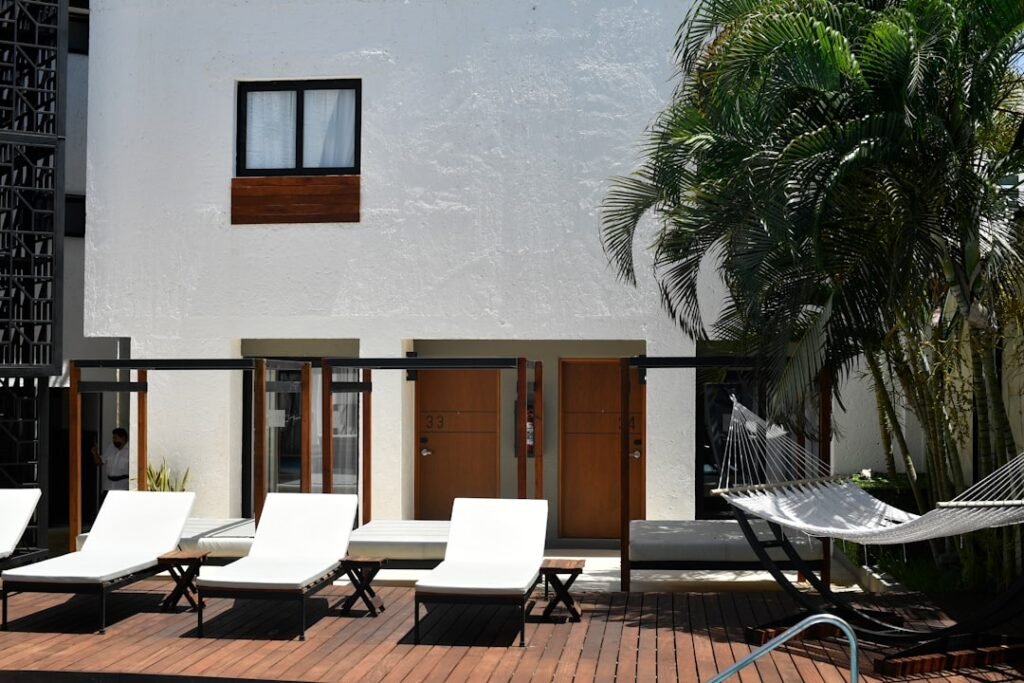 White building, lounge chairs, and hammock on a wooden deck.