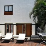 White building, lounge chairs, and hammock on a wooden deck.