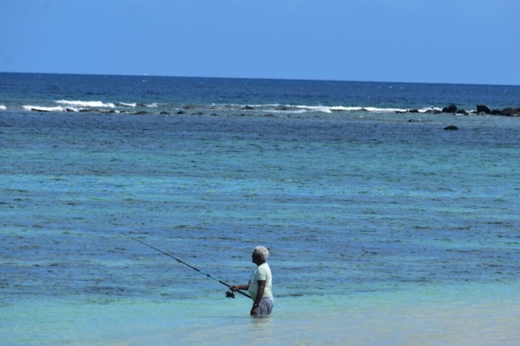 A man standing in the ocean holding a fishing rod