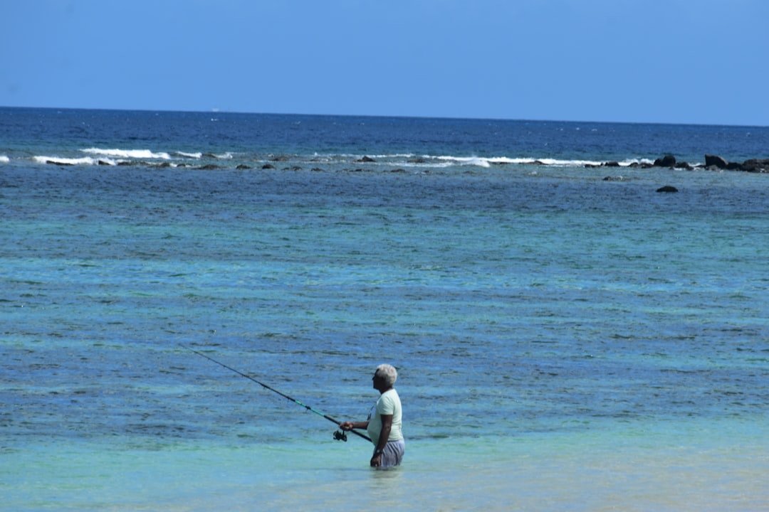 A man standing in the ocean holding a fishing rod