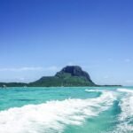 the wake of a boat in the ocean with a mountain in the background