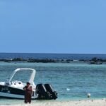 A man standing on a beach next to a boat