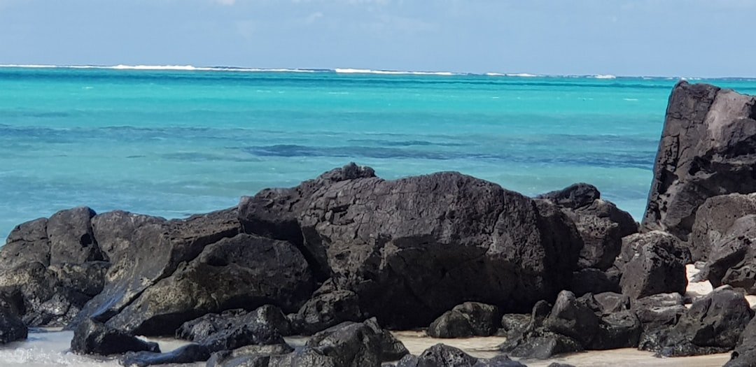 a couple of rocks sitting on top of a beach next to the ocean